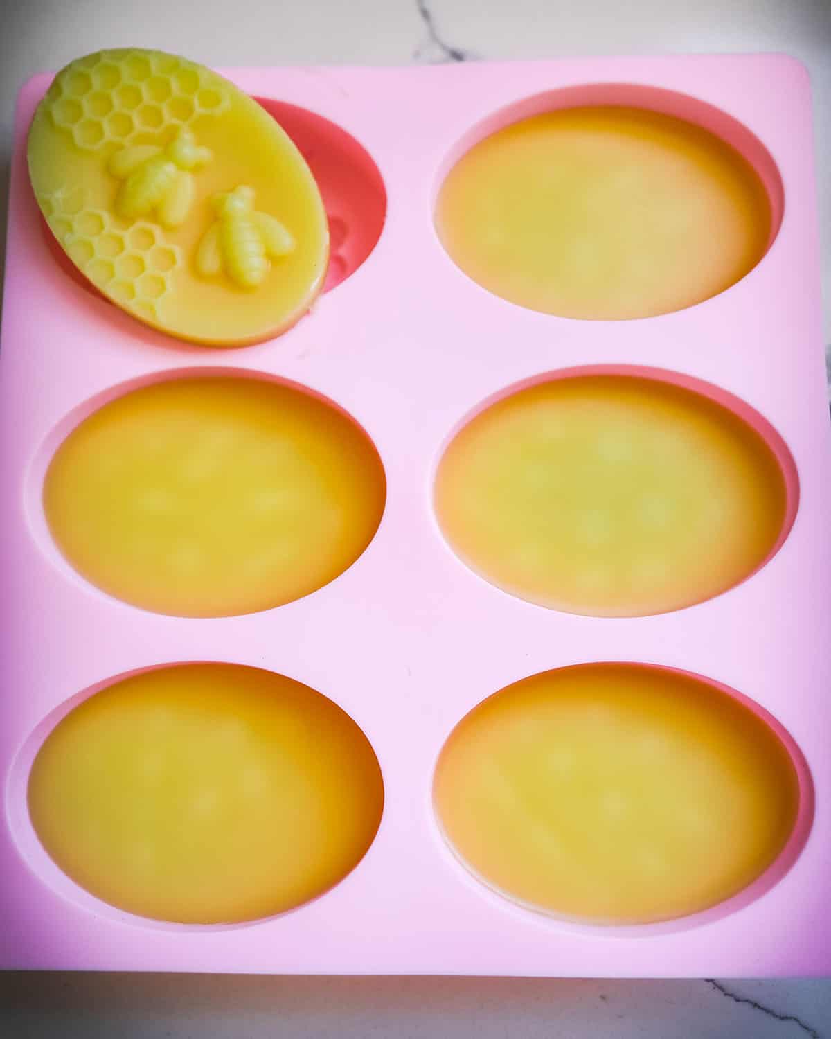 Dried and hardened lotion bars in the silicone mold, with one out showing the design on the lotion bar. 