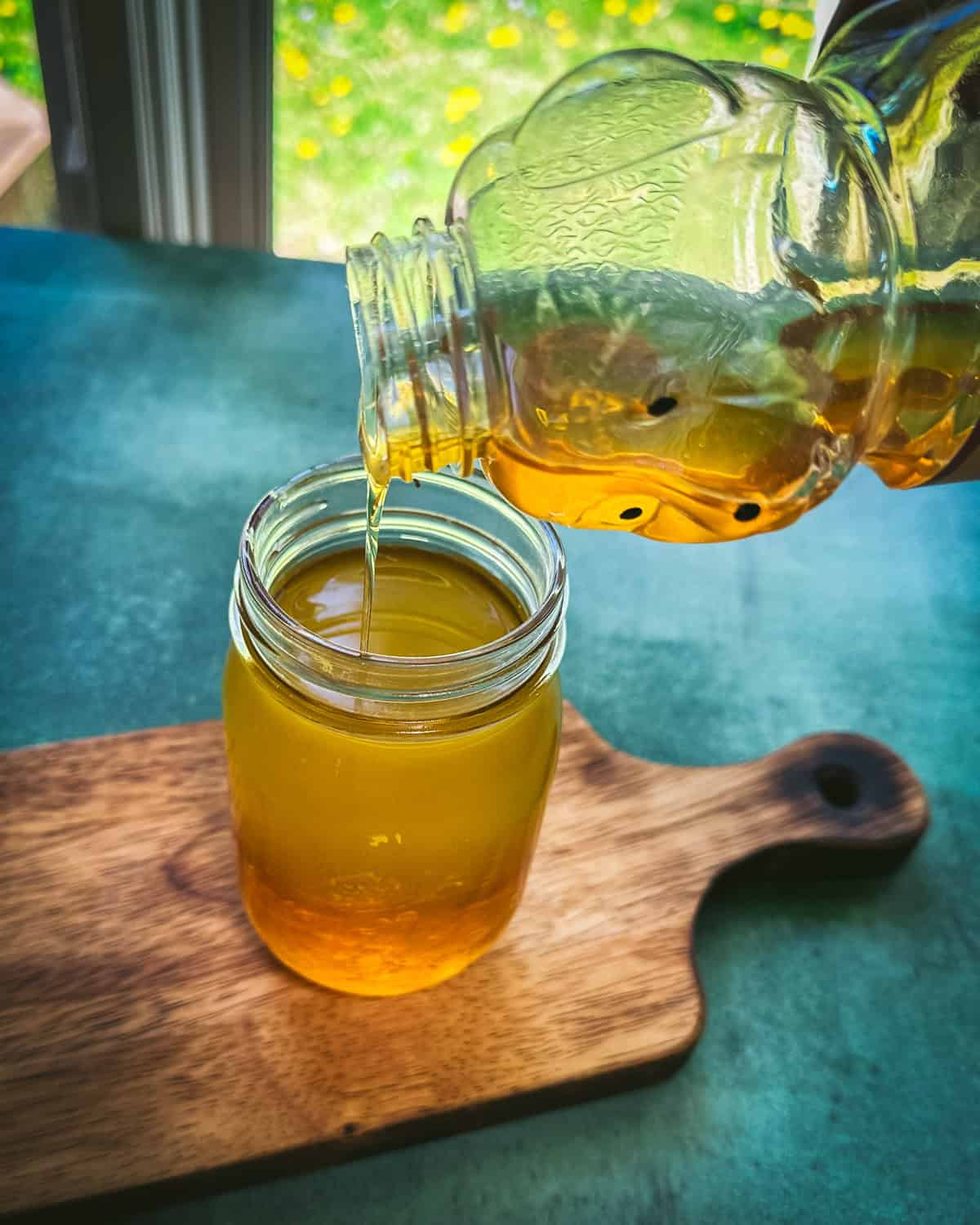 Honey pouring into the jar of dandelion tea. 