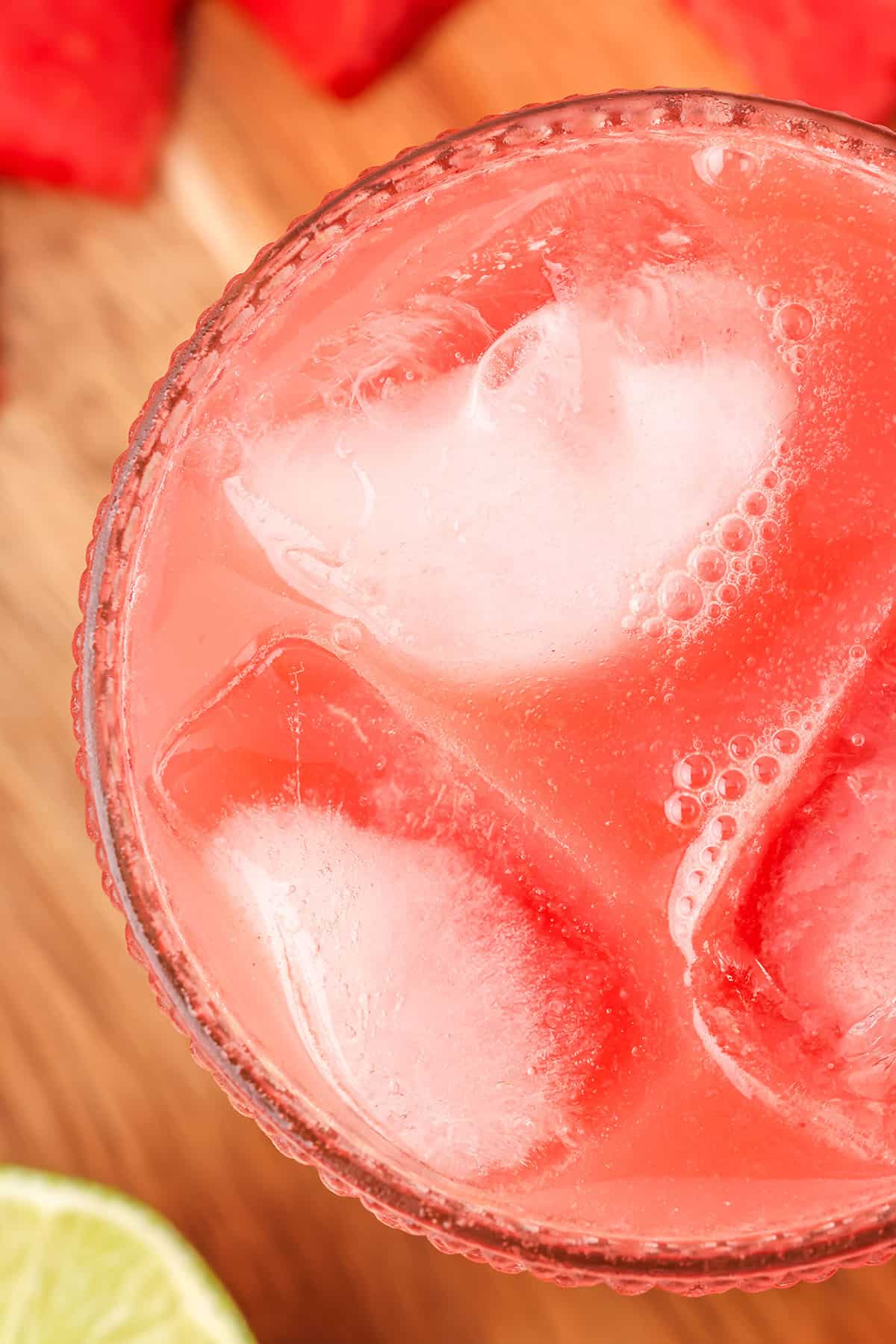 Watermelon kombucha in a glass with ice on a wood cutting board, top view. 