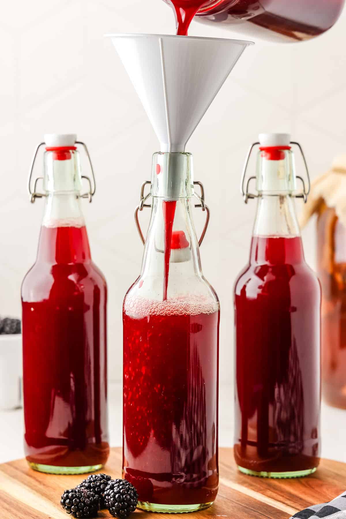 Flip top bottles with blackberry puree filling them up to the top over kombucha.