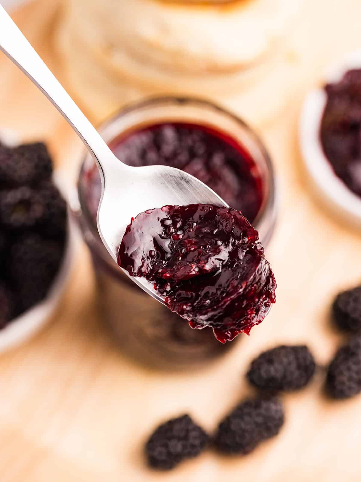 Blackberry jam lifting out of a jar on a spoon. 