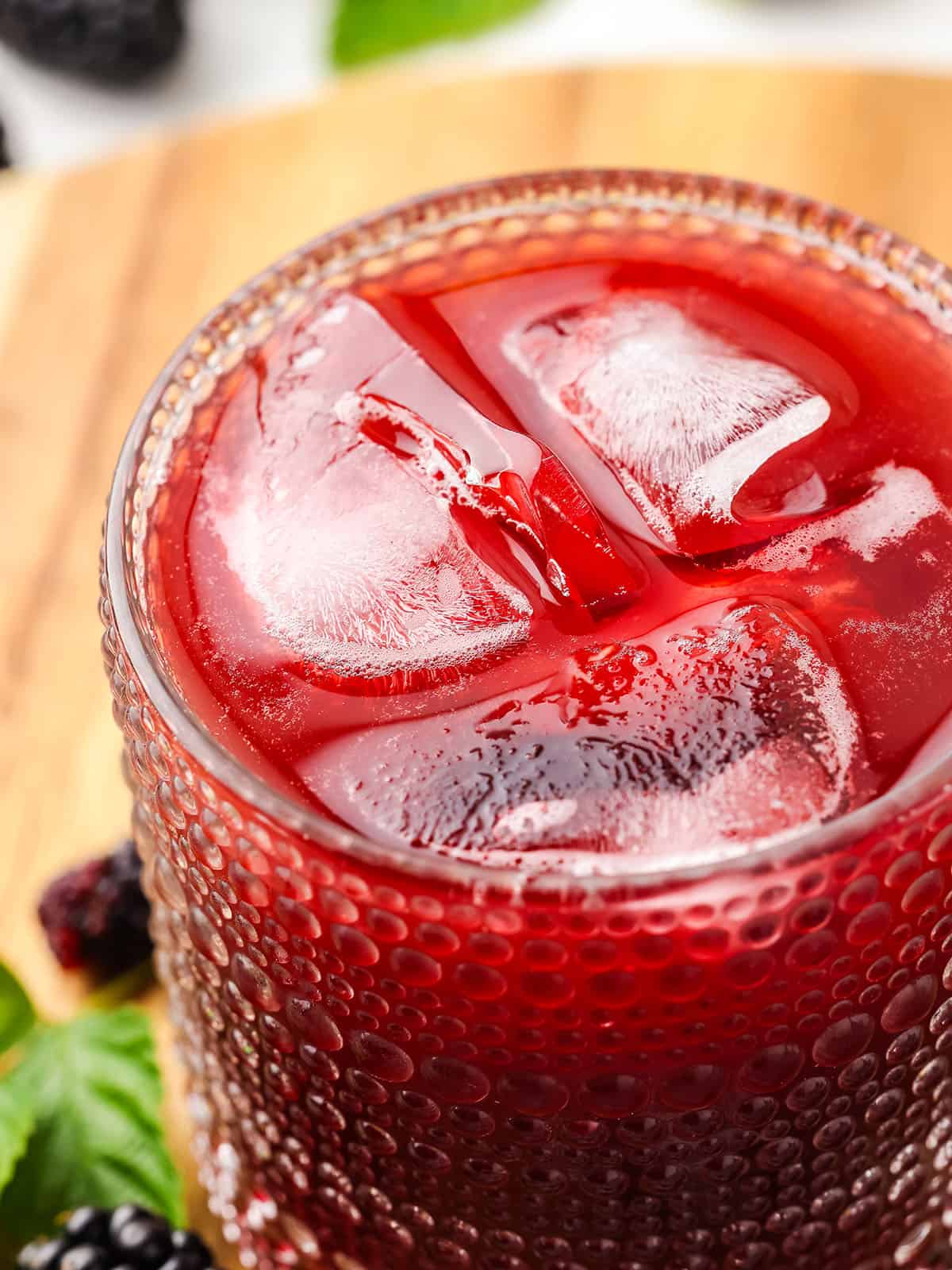 A glass of blackberry kombucha with ice, top view close up. 