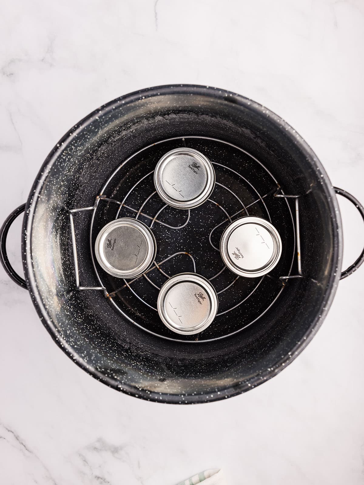 A water bath canner pot with 4 jars of jam, top view. 