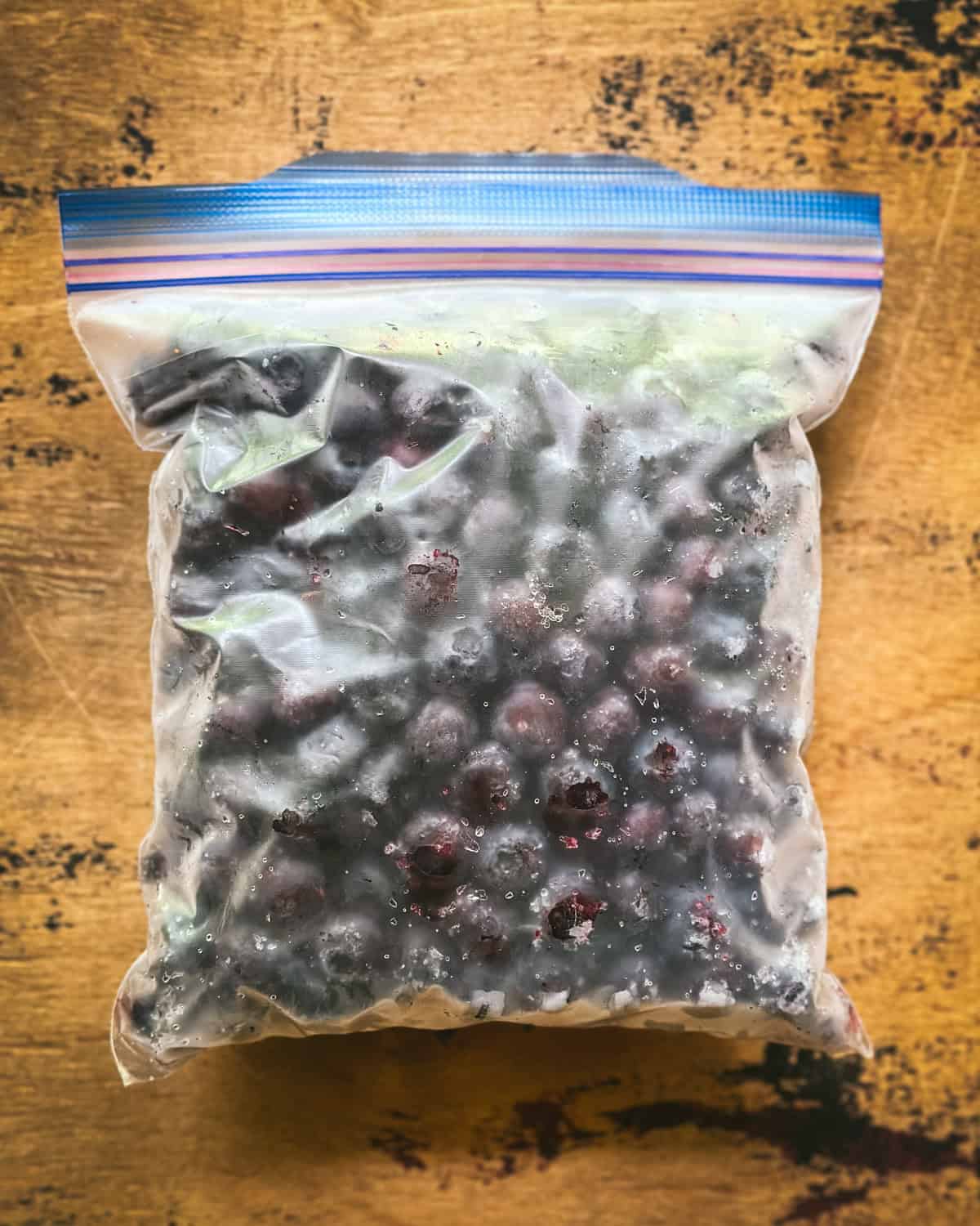 Blueberries in a zip-top freezer bag on a wood surface. 