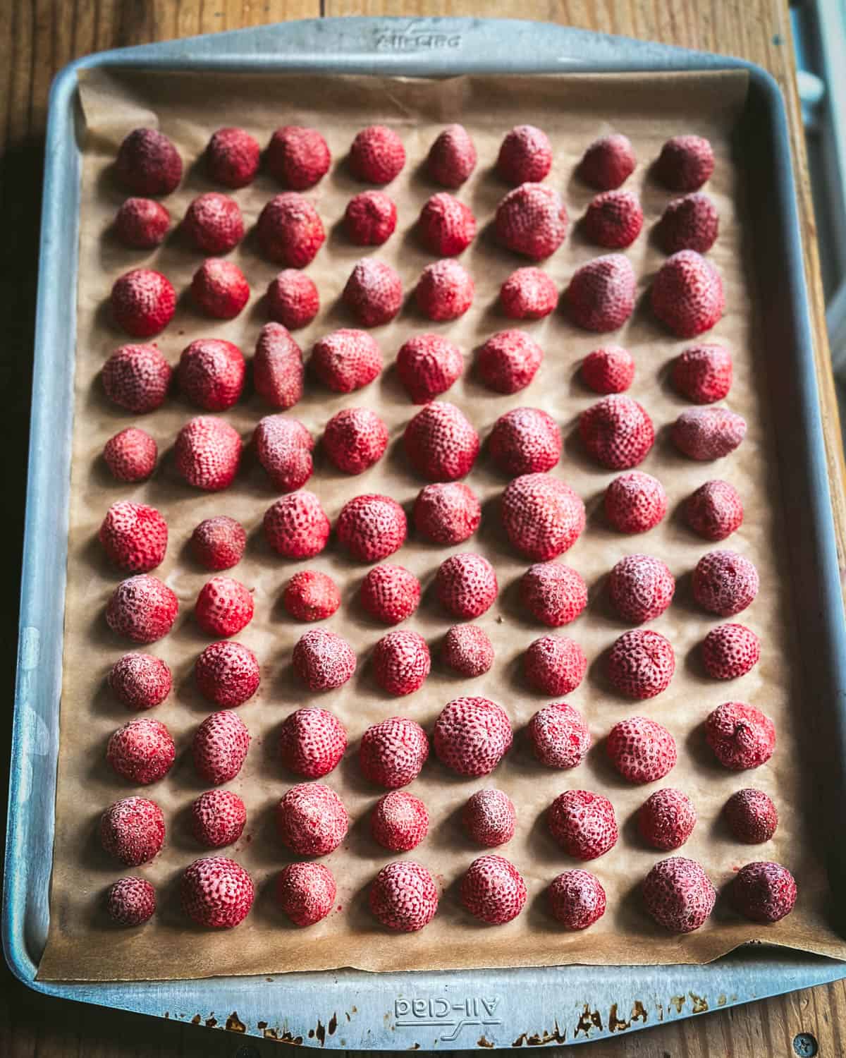 Frozen strawberries on a sheet pan lined with parchment paper. 