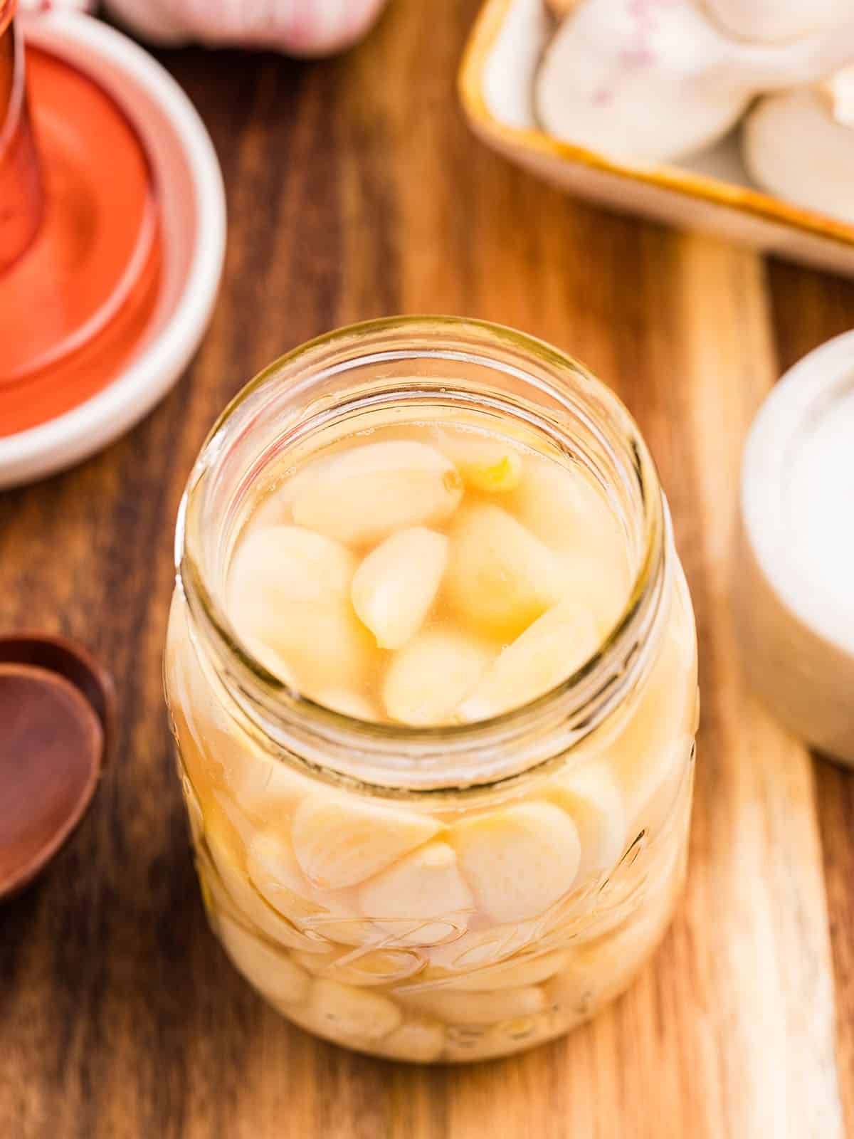 A jar of fermented garlic on a wood surface. Top view. 