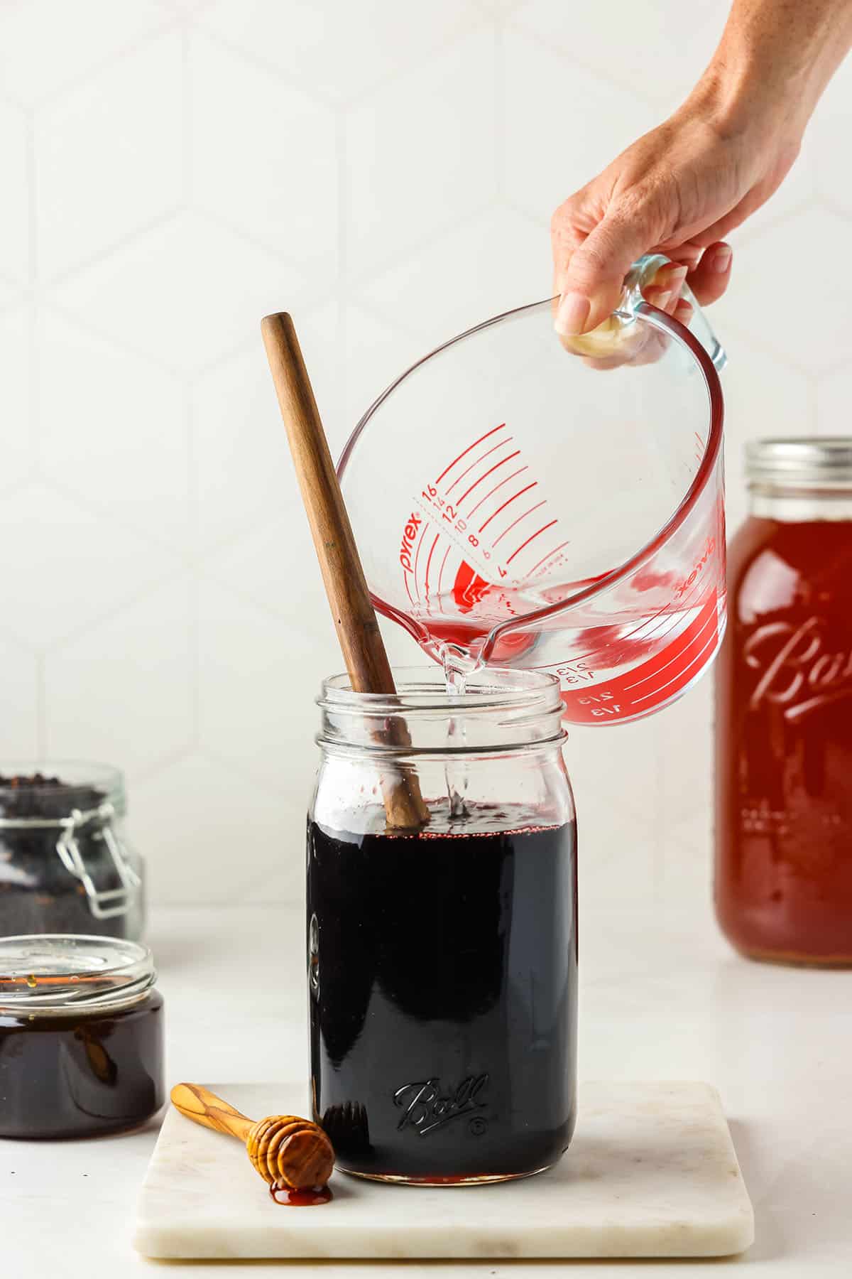 Water being added to elderberry syrup jar.