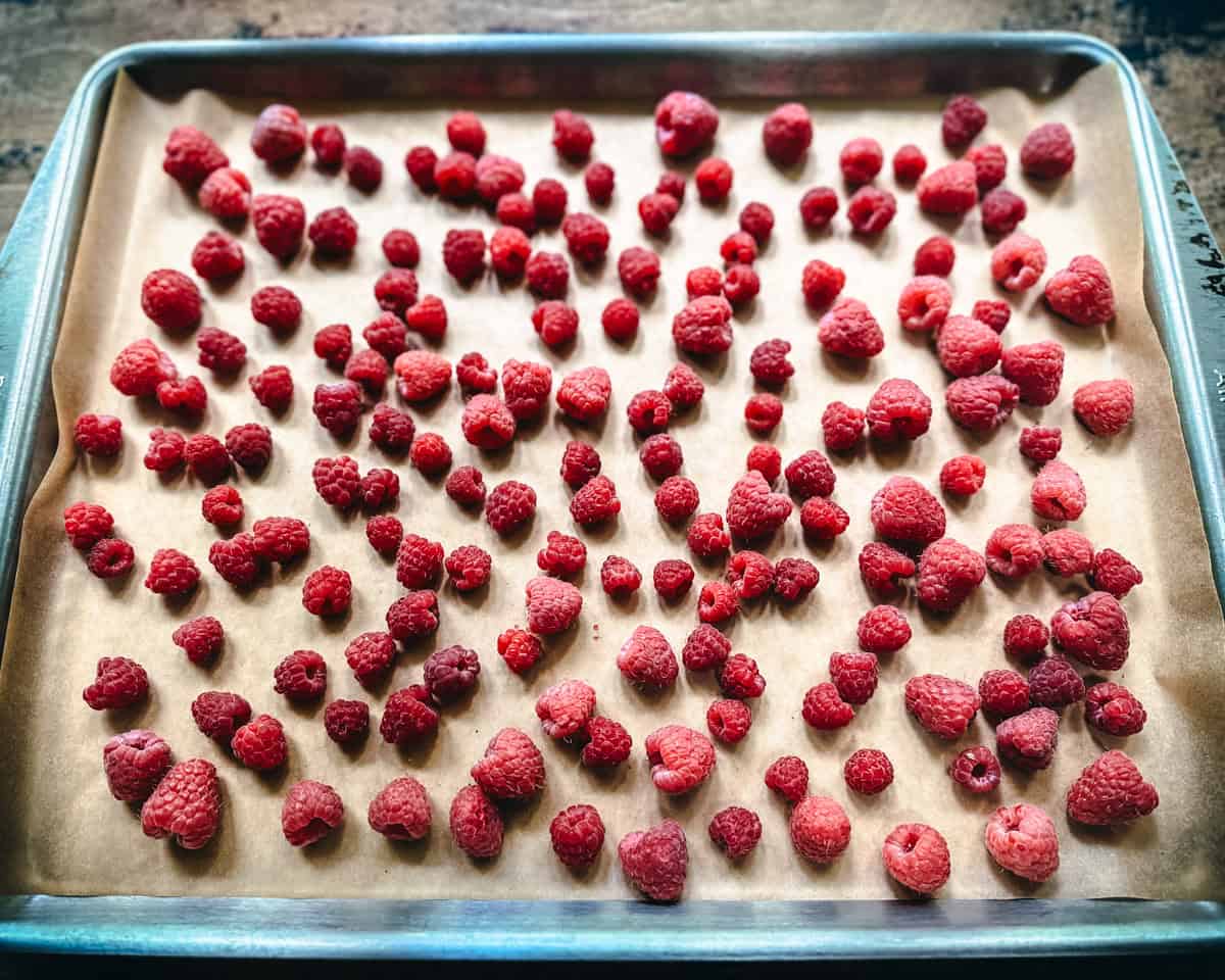 Fresh raspberries on a pan lined with parchment paper. 