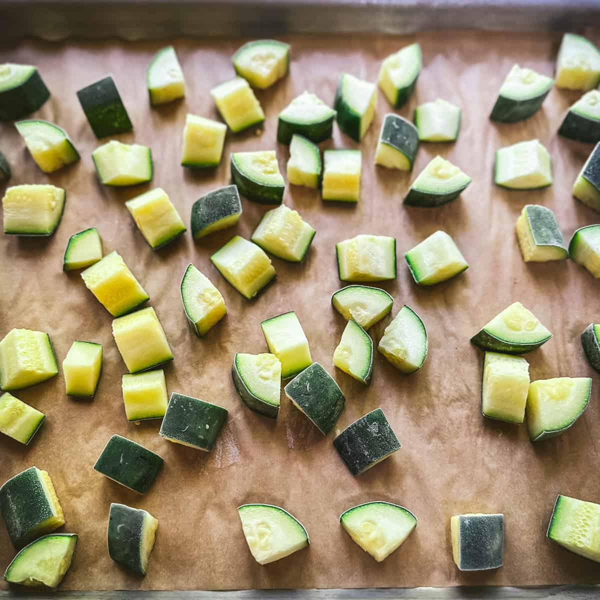 A baking sheet with frozen zucchini chunks on it. 