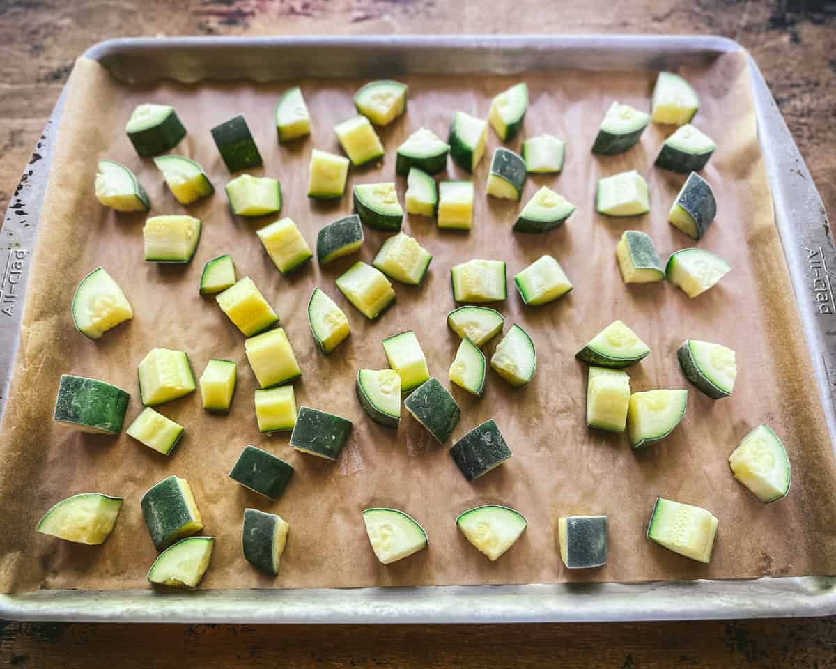 Frozen zucchini on a baking pan lined with parchment paper. 