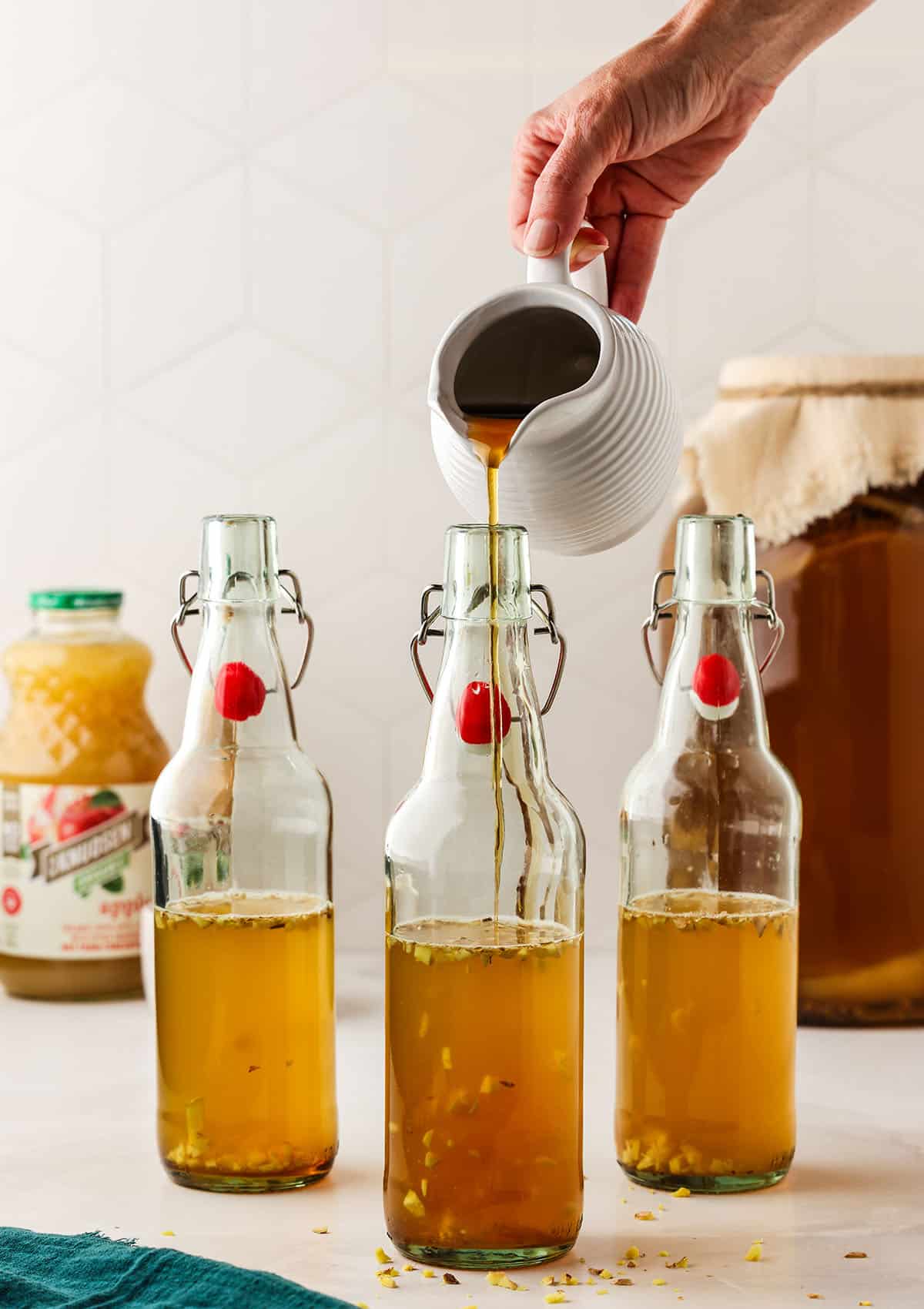 Maple syrup is poured into the bottles half-filled with kombucha. 