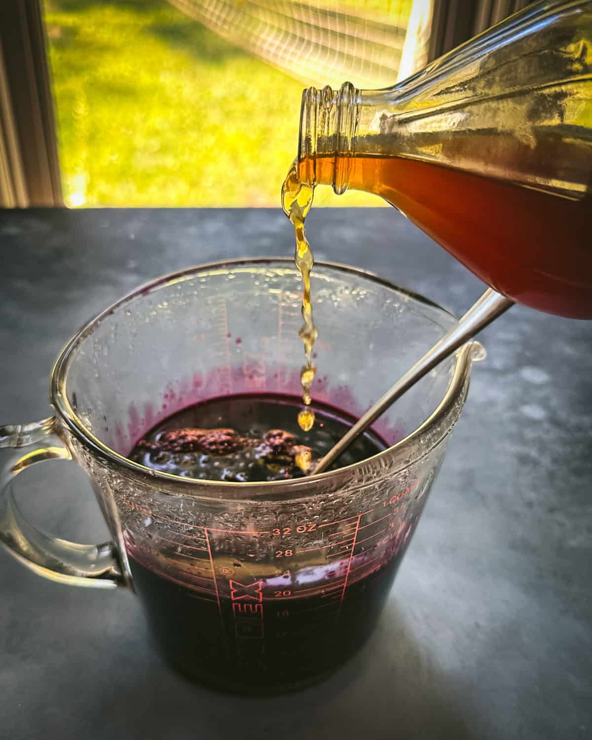 Vinegar pouring into the glass with honey and aronia infusion. 