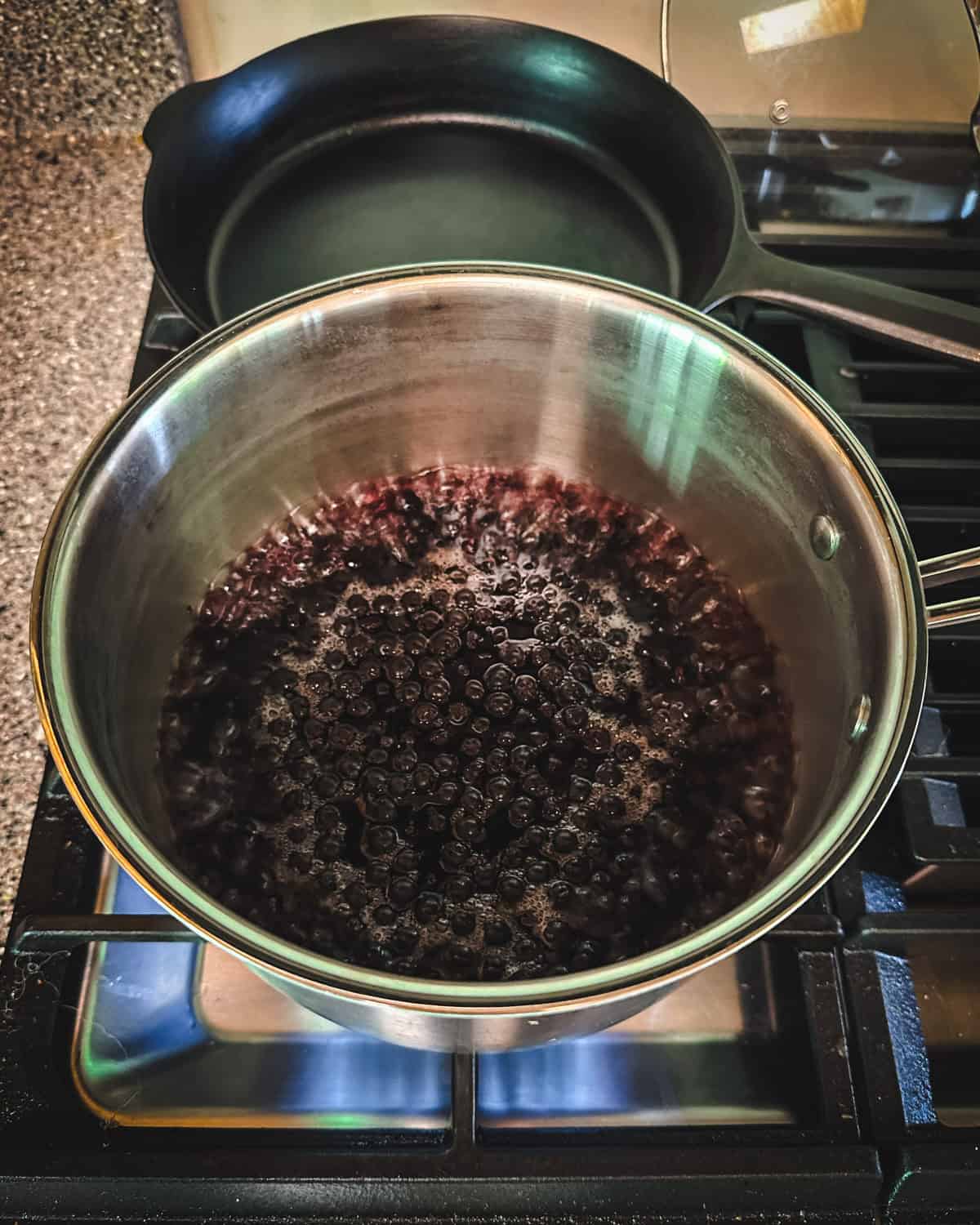 A pot on a gas stove with aronia berries boiling in water. 