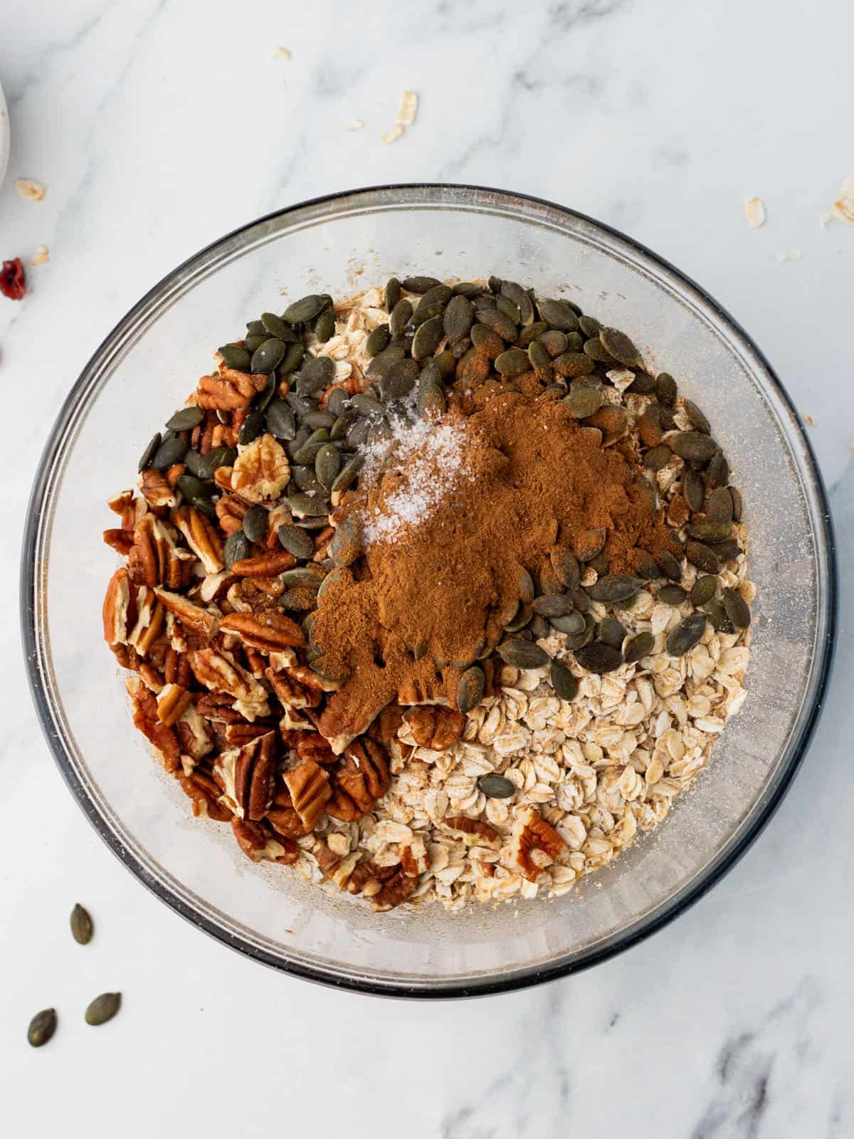 A mixing bowl with dry granola ingredients on top of the pumpkin wet ingredients. 