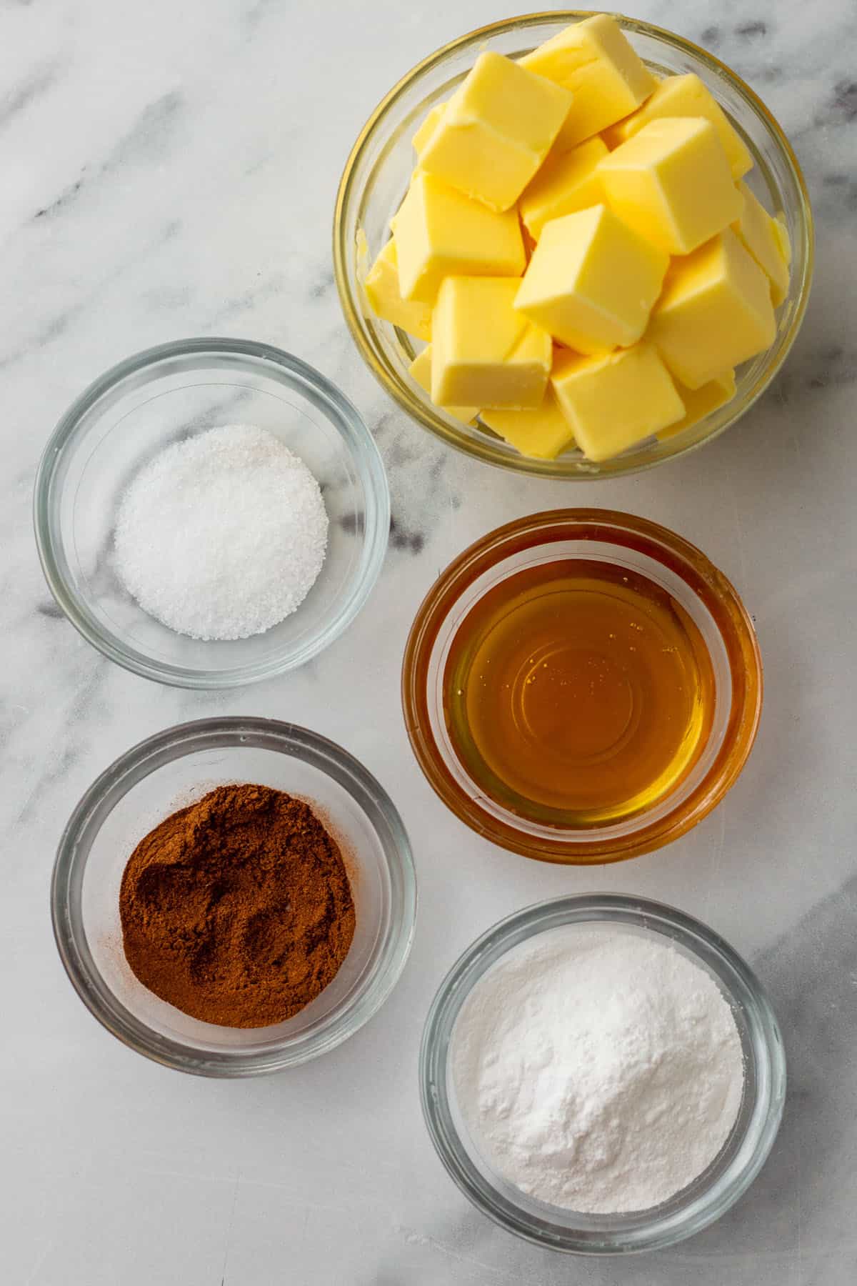 Ingredients for cinnamon butter in bowls on a white counter, top view. 