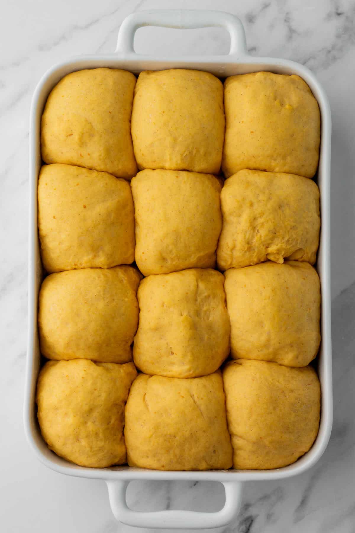 Puffy pumpkin roll dough in a baking pan. 