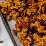 A close up of pumpkin granola with pecans on a lined pan.