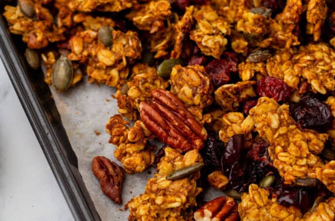 A close up of pumpkin granola with pecans on a lined pan.