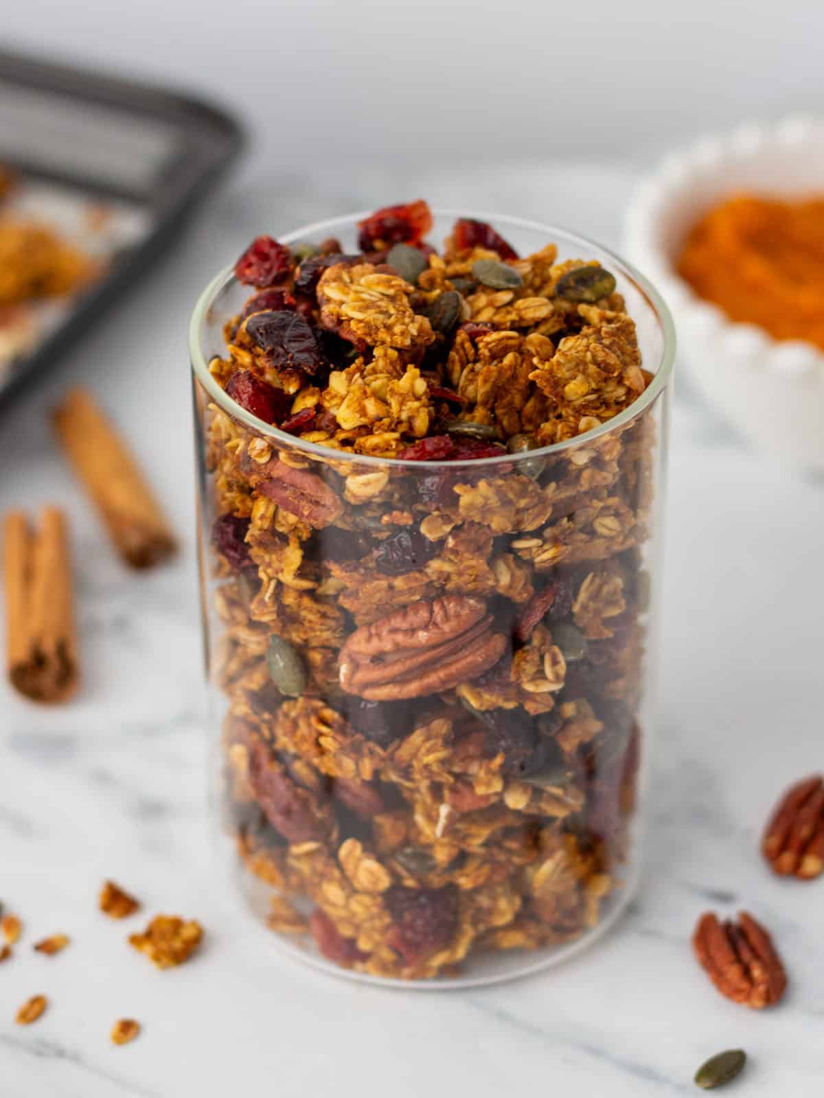 Pumpkin granola in a jar on a white counter. 