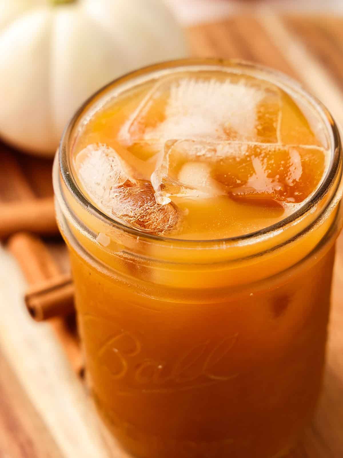 A jar of pumpkin kombucha with ice, top view. 