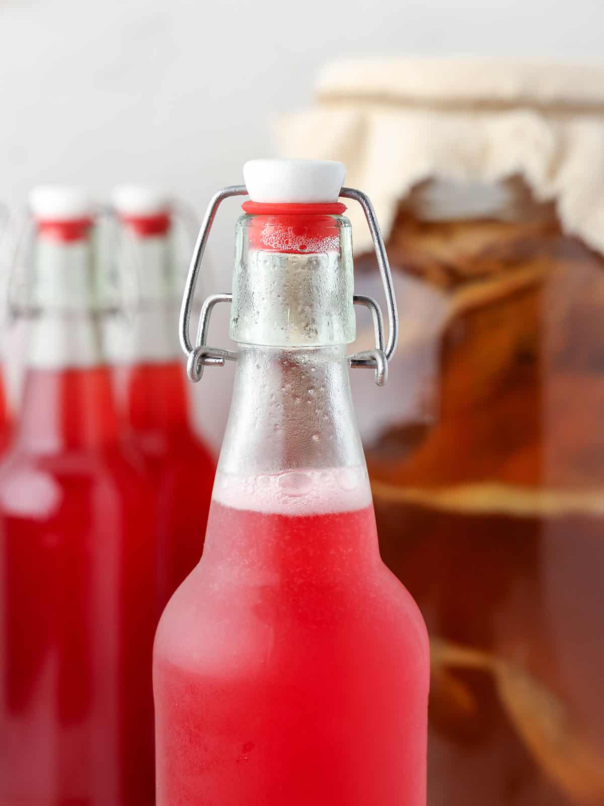 Cranberry kombucha in a bottle forming bubbles.