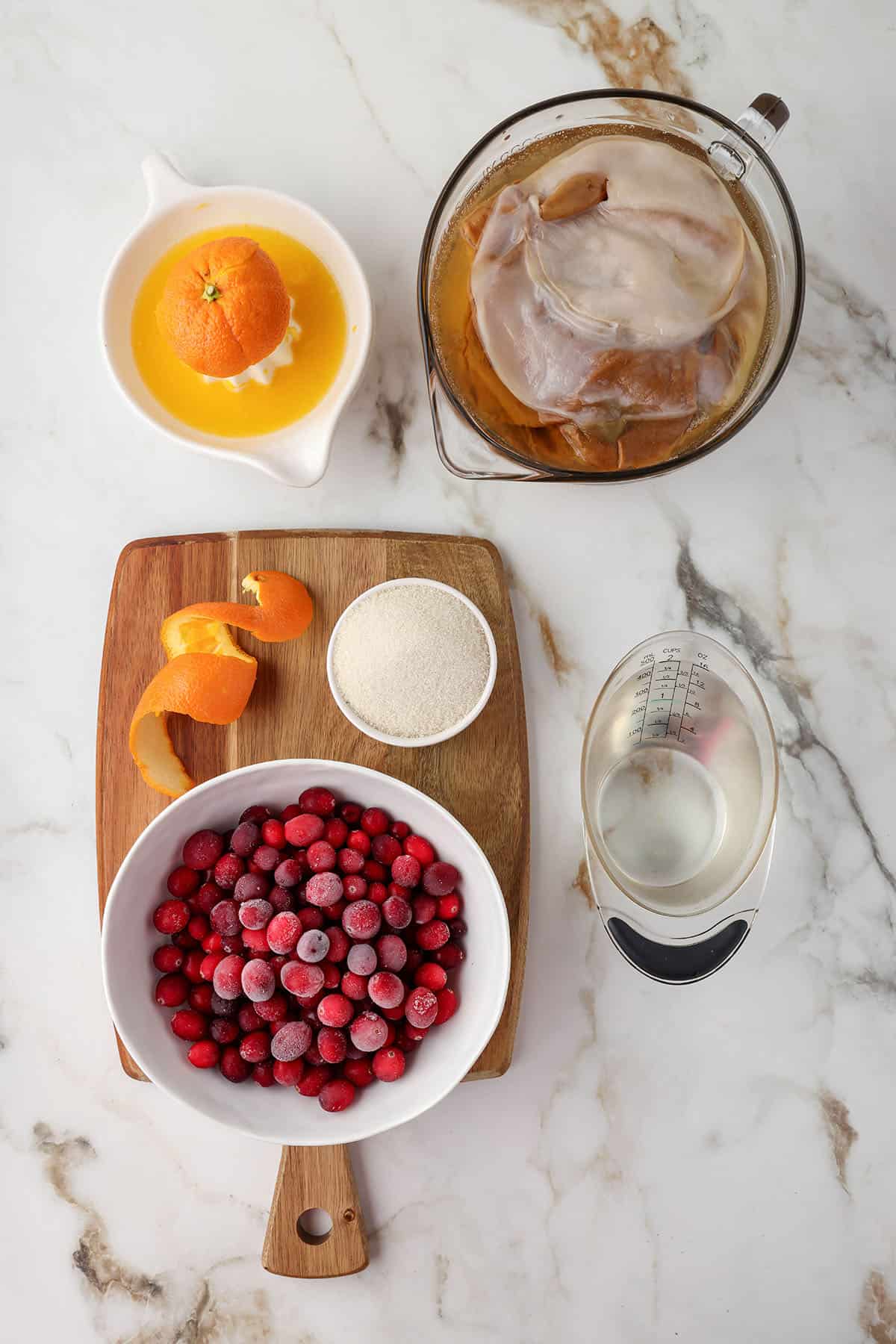 Cranberry kombucha ingredients on a white counter, top view.
