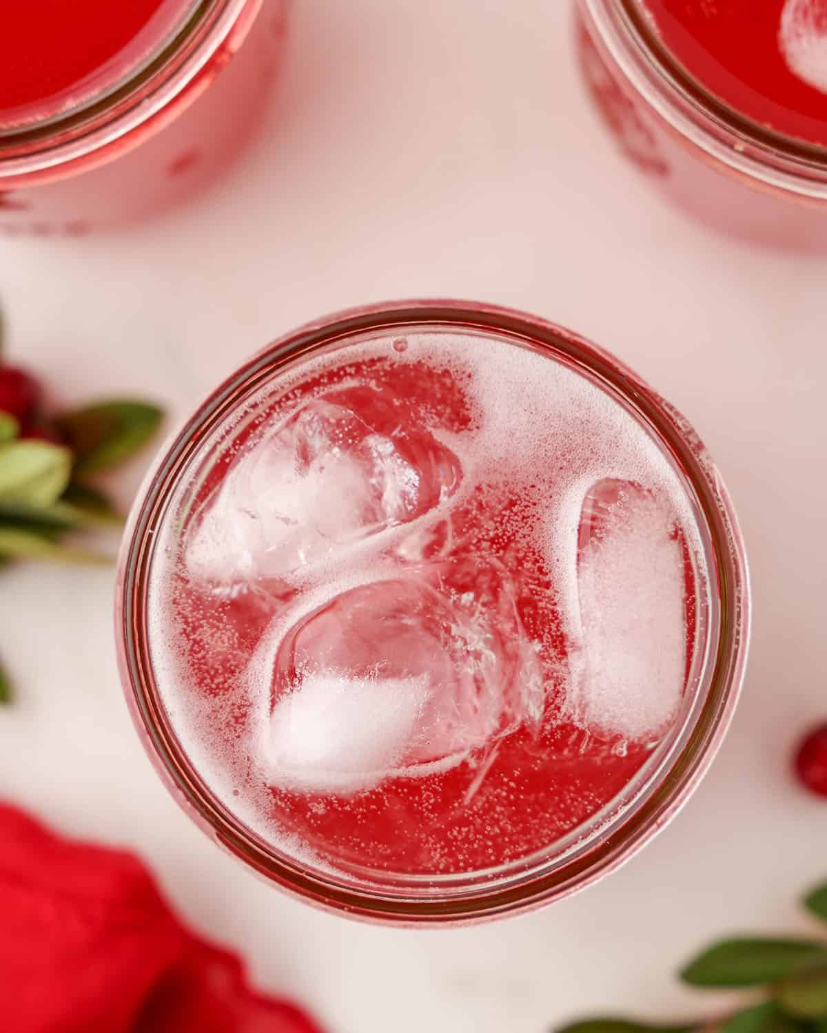 Cranberry kombucha with ice in a jar, top view.