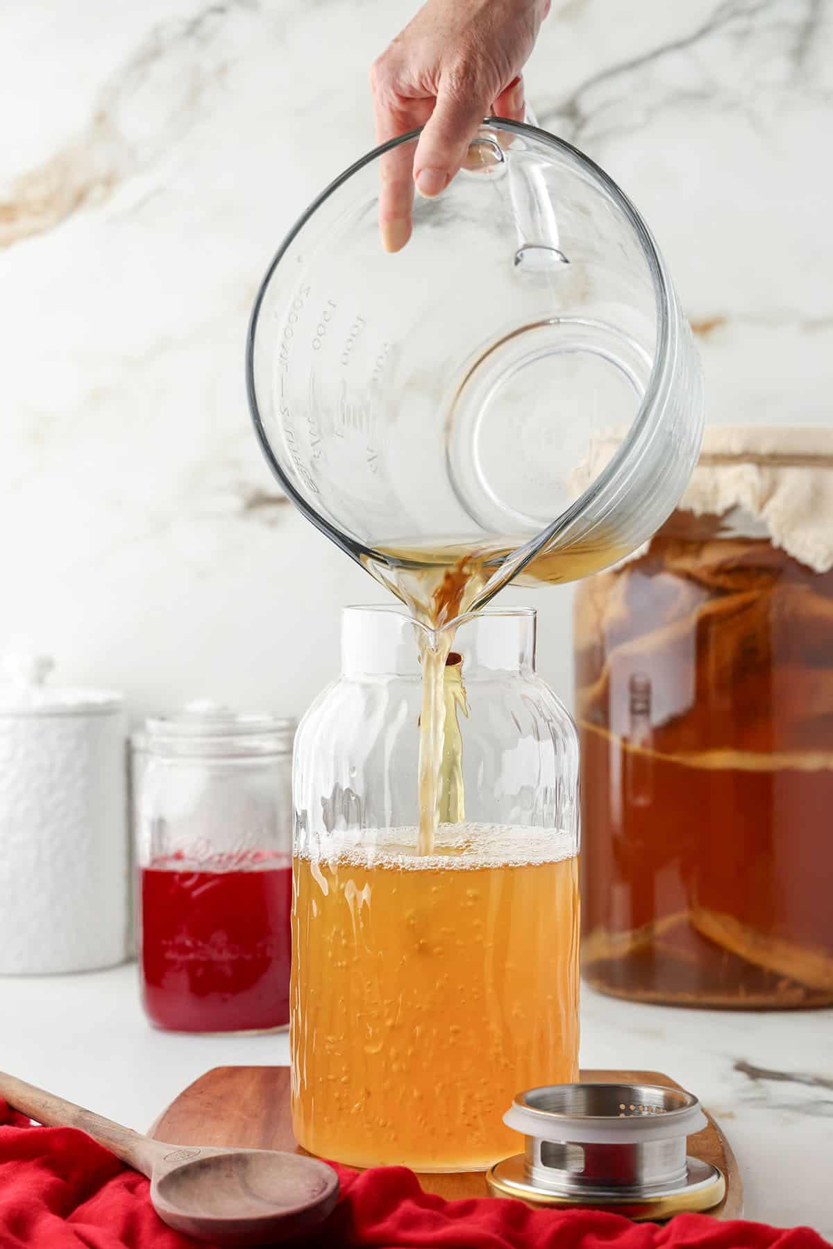 Kombucha pouring into a large pitcher.